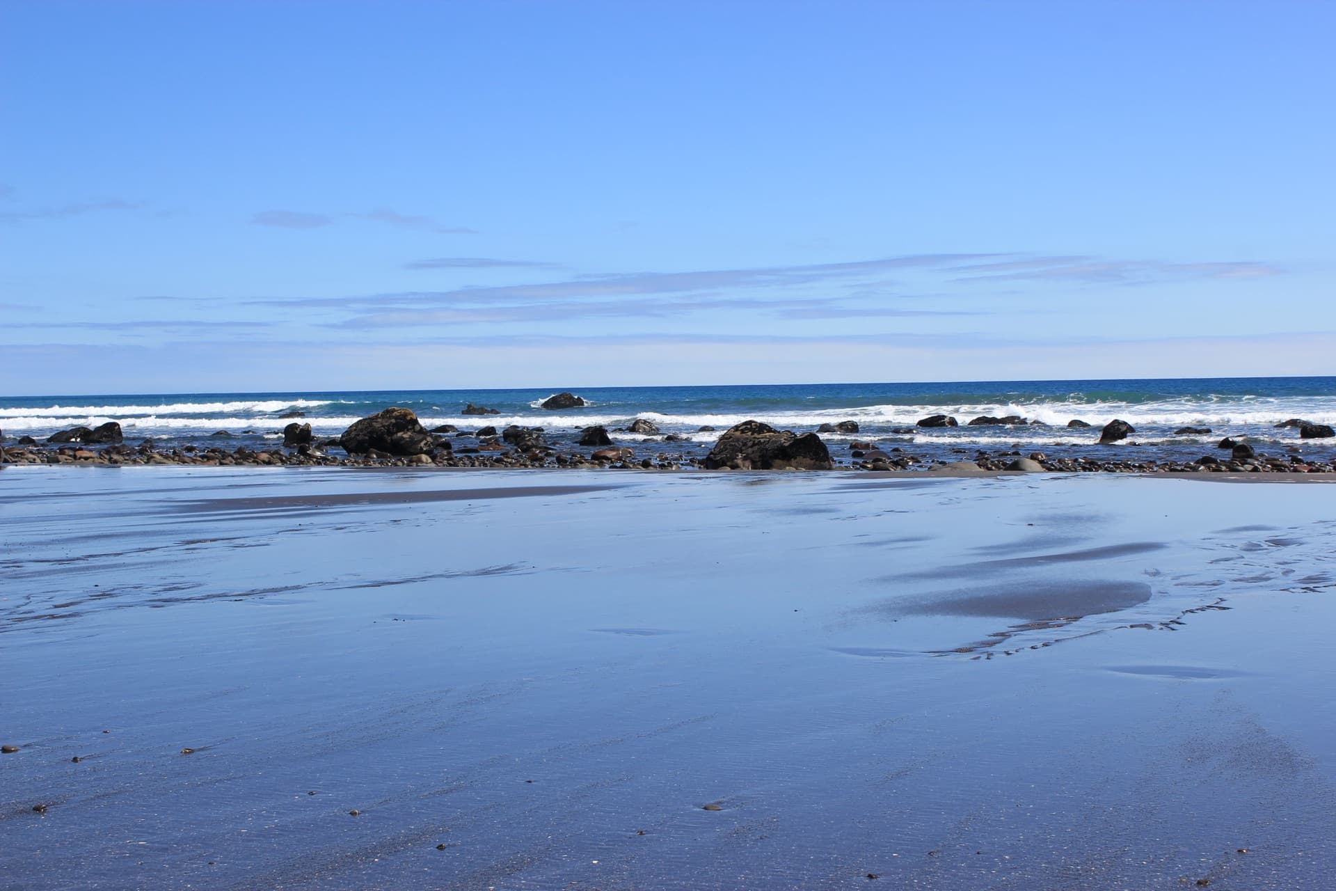 Taranaki coastline with rocky shoreline and blue sky