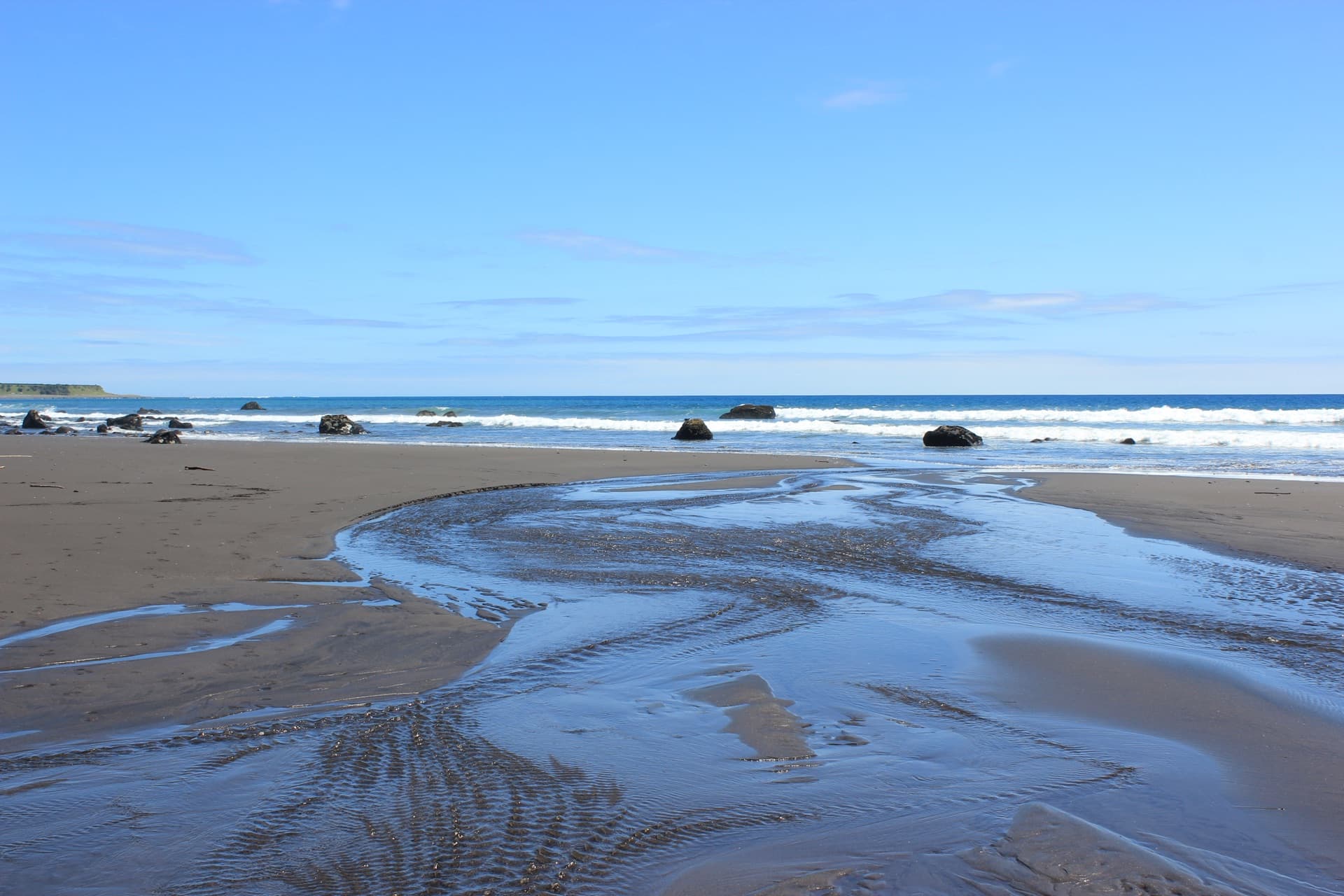 Taranaki coastline with tidal patterns on black sand